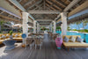 Outdoor lounge area with tables, chairs, and a pool in the background