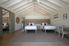 Bedroom with two beds, a table, and chairs under a vaulted ceiling.