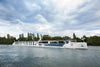 Passenger boat on a river with trees and clouds in the background
