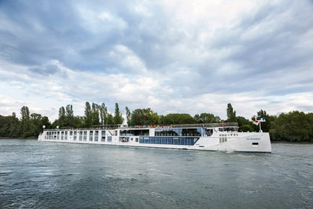 Passenger boat on a river with trees and clouds in the background