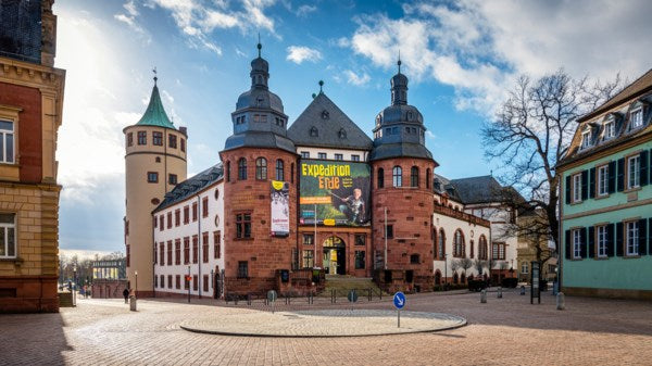 Historic building with a clock tower and people walking around in a town square.