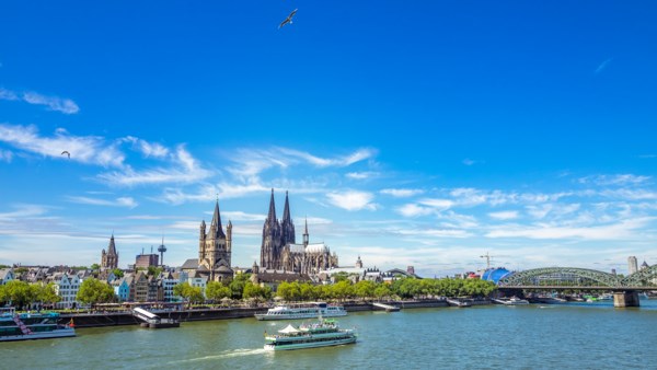 Cityscape with a large cathedral and river, under a blue sky.