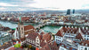Cityscape with historic buildings and a river, featuring a prominent clock tower.