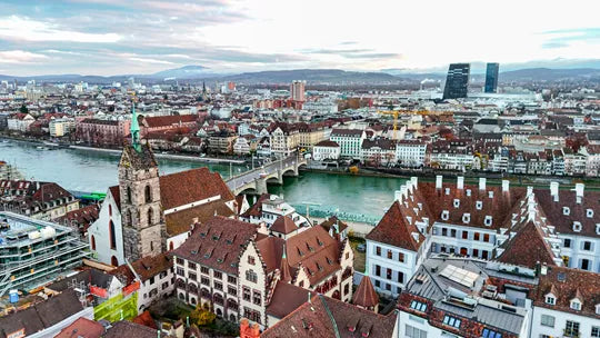 Cityscape with historic buildings and a river, featuring a prominent clock tower.