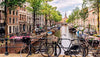 Canal scene in Amsterdam with bicycles, buildings, and boats.