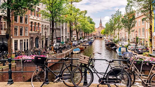 Canal scene in Amsterdam with bicycles, buildings, and boats.