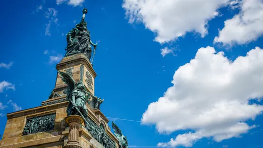 Statue on a tower against a blue sky with white clouds