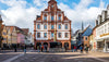 Town hall building in a European town square with people walking around.