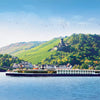 Cruise ship on a river with a scenic hillside and castle in the background