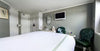 Modern hotel room with bed, chairs, and television.