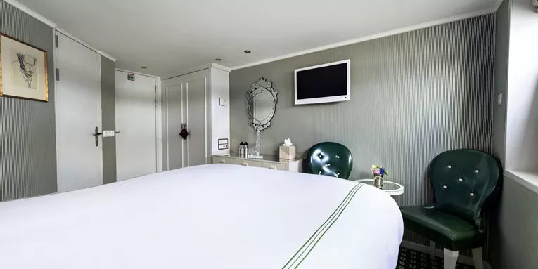 Modern hotel room with bed, chairs, and television.