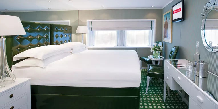 Modern hotel room with a bed, desk, and decorative elements.